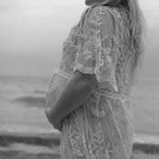 A maternity picture of a woman holding her stomach at the beach